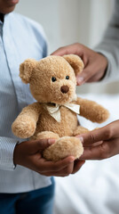 Hands gently holding a small teddy bear creating an emotional scene of care and comfort.
