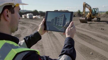 Construction worker holds tablet displaying 3D building model on site. Illustrates use of augmented reality in modern construction planning and architectural visualization. - Powered by Adobe