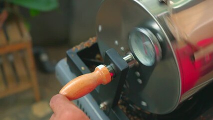 Process of manual coffee roasting, using stainless steel drum coffee roaster, sometimes checking the roast level of the beans