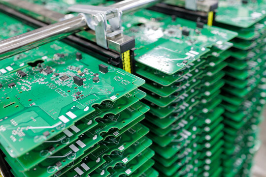 Stack of assembled circuit boards in metal rack at modern electronics factory