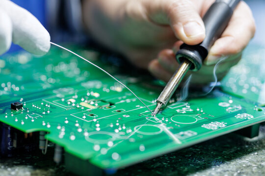 Technician Hand Soldering Electronic Circuit Board in Modern Manufacturing Workshop