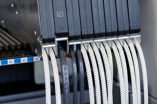 Feeder tapes with SMD parts on SMT pick and place machine in electronics factory