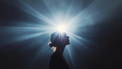 Silhouette of a woman's head with a radiant light shining on her face against a dark background conveying mental health and wellness with a sense of hope and positivity.