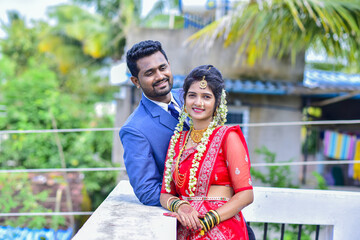 Naklejka premium Indian wedding couple standing together outdoors, bride and groom dressed in traditional attire, celebrating marriage and togetherness in Indian culture.