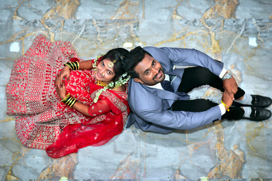 Top view of Indian wedding bride and groom looking up, dressed in traditional attire, captured from overhead angle during marriage ceremony. - Powered by Adobe