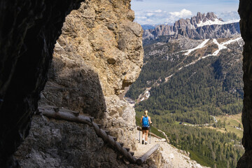 Hiker emerging from historic mountain tunnel in the Dolomites, Italy