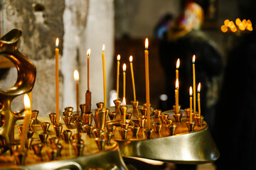 Candles in a Christian Orthodox church background. Flame of candles in the dark sacred interior of the temple