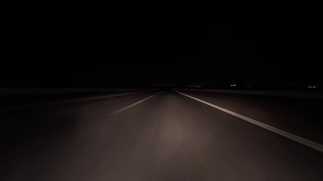 Night highway drive hyperlapse with strong motion blur and light trails, filmed from a moving car on an empty road. Sense of speed, travel, freedom, and long-distance transportation