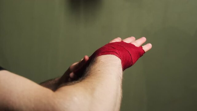 Boxer wraps wrists in preparation for hitting speed bag. Athlete strengthens muscles and protects joints before training with special equipment