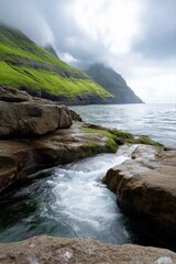 Obraz premium Scenic rocky coastline with lush green hills and cloudy sky