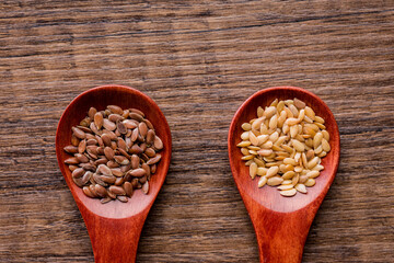 Brown and gold linseed or flaxseed . Healthy flax seed on wooden spoon on wooden table. Top view.