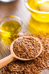 Brown linseed or flaxseed and oil. Healthy flax seed on wooden spoon on wooden table.