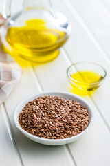 Brown linseed or flaxseed and oil. Healthy flax seed in bowl on white table.