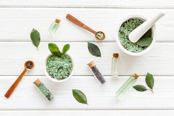 Obraz na płótnie Canvas Homemade organic cosmetics products - tea tree essential oil and sea salt with green leaves, top view