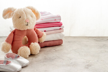 Pile of washed baby clothes with booties and toy on a table, close up