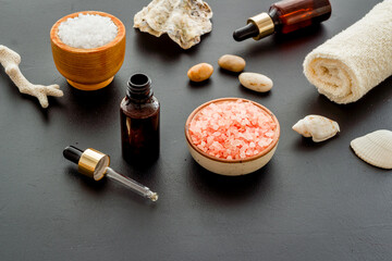 Spa treatment body care cosmetics close up. Sea salt in bowl and essential oil on bottle