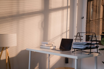 Home office workspace with laptop and sunlight shadows