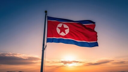 The national flag of a country with a red star flies against a sunset sky