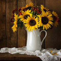 Sunflowers  and heleniums bouquet in white pitcher on rustic wood