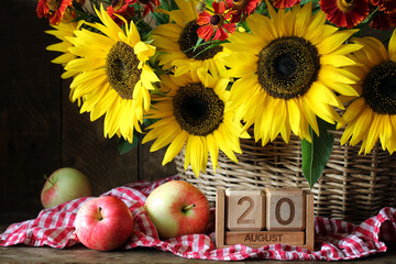 August 20th. sunflowers in basket and wooden perpetual calendar, summer holiday or event date. garden flowers and apples.