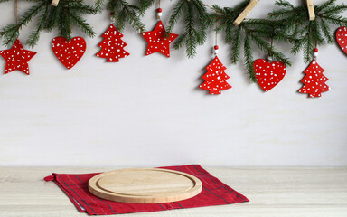 Christmas mockup. empty table with cutting board and garland of fir branches and red flat ornaments on clothespins