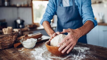 Baker in blue apron kneads dough on floured table in cozy kitchen illustrating artisan bread preparation homemade cooking and warm culinary atmosphere