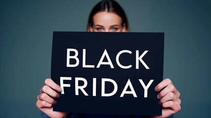 Smiling woman in blue sweater holds black friday sign against gradient background inviting customers to enjoy seasonal discount shopping and fashion sale promotion