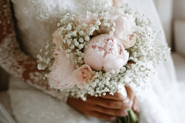 Fototapeta premium Bridal bouquet featuring pink peonies and white flowers held by a woman in wedding attire