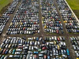 Top down aerial view of an abandoned car graveyard filled with old, damaged and unused vehicles arranged in dense rows. Concept of decay, waste, recycling and forgotten transport