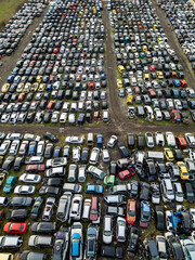 Top down aerial view of an abandoned car graveyard filled with old, damaged and unused vehicles arranged in dense rows. Concept of decay, waste, recycling and forgotten transport