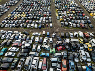 Top down aerial view of an abandoned car graveyard filled with old, damaged and unused vehicles arranged in dense rows. Concept of decay, waste, recycling and forgotten transport