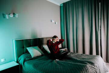 Naklejka premium Young woman studies on laptop while sitting on bed in her room at night