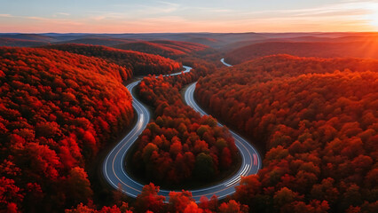 Winding asphalt road through vibrant red autumn forest at sunset fall trees
