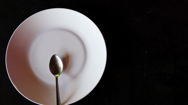 empty dish and spoon top view on black background with copy space