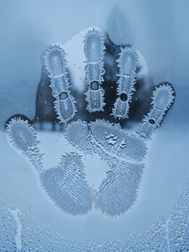 Frosted handprint on chilly glass window in winter environment  
