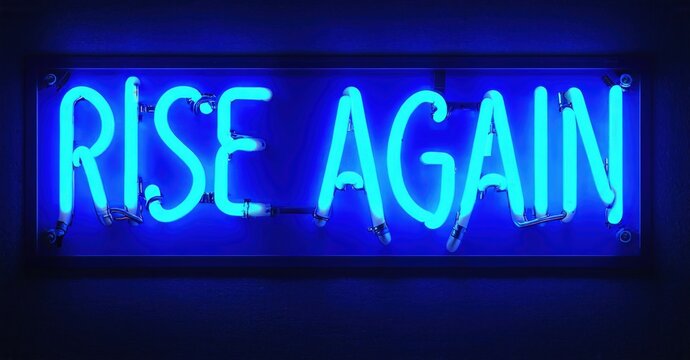 Bright neon sign displays text RISE AGAIN. Dark background emphasizes glowing blue illumination. Simple, motivational message presented boldly.