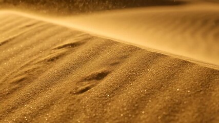 Wind blowing fine sand across golden desert dunes with footprints, showing abstract natural movement and erosion footage.
