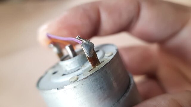 Macro detail of a purple copper wire attached to the metal terminal of a small electric dynamo motor engine