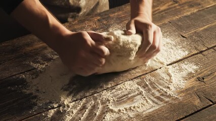Hands kneading dough on wooden table