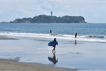 潮が引いた片瀬西浜海岸で海に入るサーファー