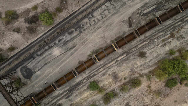 Aerial view of a long train on the tracks cuts through the arid landscape, showing a stark contrast between industrial transport and the natural desert, Phoenix, Arizona, United States.