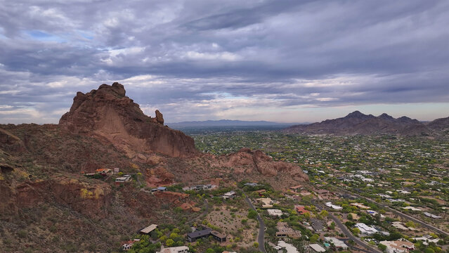 Aerial view of the rugged, rust-colored rock formations of Papago Park juxtapose with the sprawling green urban landscape, a testament to nature's artistry, Phoenix, Arizona, United States.