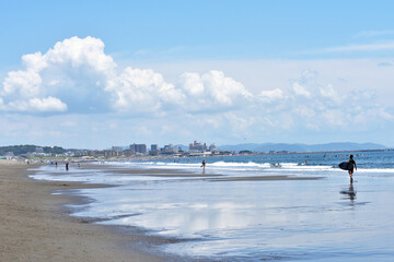 潮が引いた片瀬西浜海岸で海に入るサーファー
