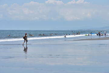 潮が引いた片瀬西浜海岸で海に入るサーファー