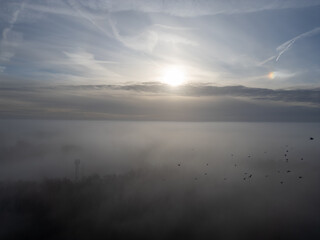 Obraz premium Foggy Landscape with Sun Peeking Through Clouds