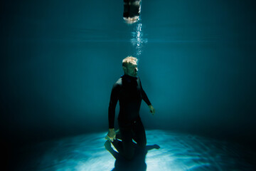 Senior diver with nose clip training breath hold underwater 