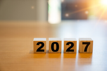 Wooden cubes displaying the year 2027 on a wooden table. Concept image representing future...