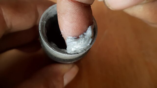 Close up of male finger dipping into gray thermal paste grease for computer processor cooling application
