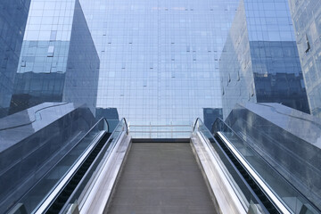 The exterior of a glass escalator building in the city.