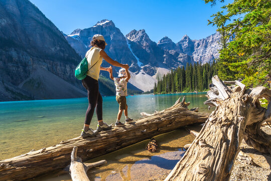 Mother and child balancing on log at moraine lake, banff national park
